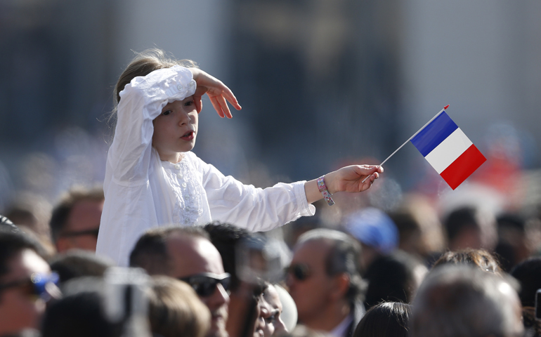 A girl holds France's flag as Pope Francis leads his general audience in St. Peter's Square at the Vatican April 12. (CNS/Paul Haring)