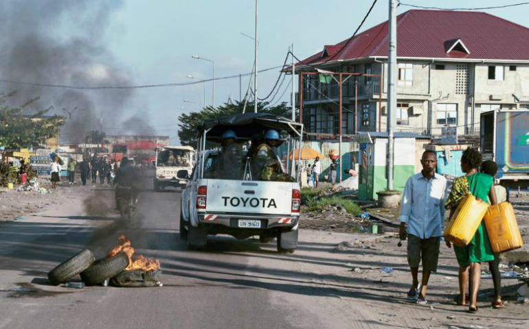 Peacekeepers drive past burning tires as they patrol protests against President Joseph Kabila in Kinshasa, Congo, April 10. (CNS photo/Robert Carrubba, Reuters)