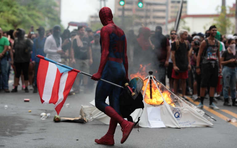 A man dressed as Spider-Man walks past a burning barricade in San Juan, Puerto Rico, May 1, to protest the government's austerity measures in the face of mounting debt. (CNS/Reuters/Alvin Baez)