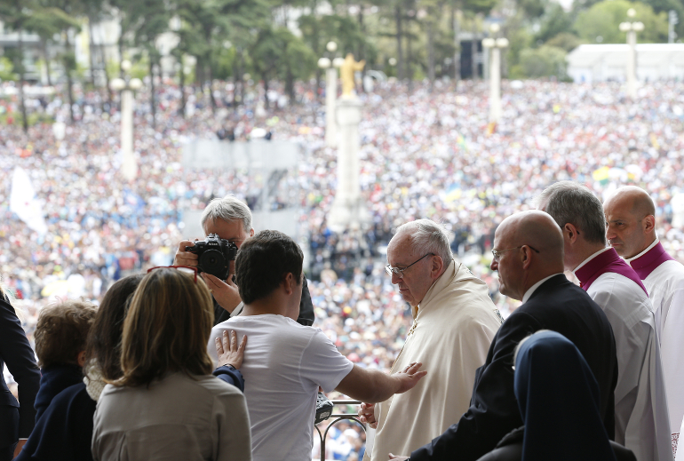 A man reaches to touch Pope Francis after the pope blessed the sick with the Eucharist at the conclusion of the canonization Mass of Sts. Francisco and Jacinta Marto, two of the three Fatima seers, at the Shrine of Our Lady of Fatima in Portugal May 13. The Mass marked the 100th anniversary of the Fatima Marian apparitions, which began on May 13, 1917. (CNS photo/Paul Haring)