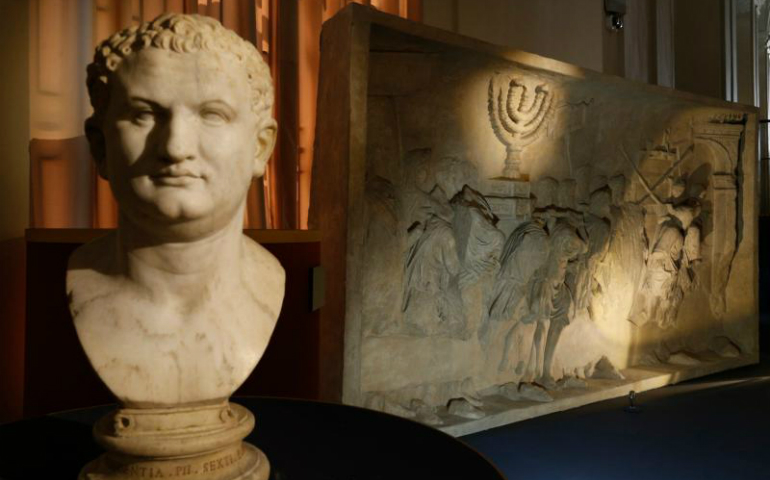 A bust of Roman Emperor Titus is pictured next to a replica of the 1st-century Arch of Titus, showing Roman soldiers carrying the menorah, in a exhibition at the Vatican May 15. (CNS/Paul Haring)