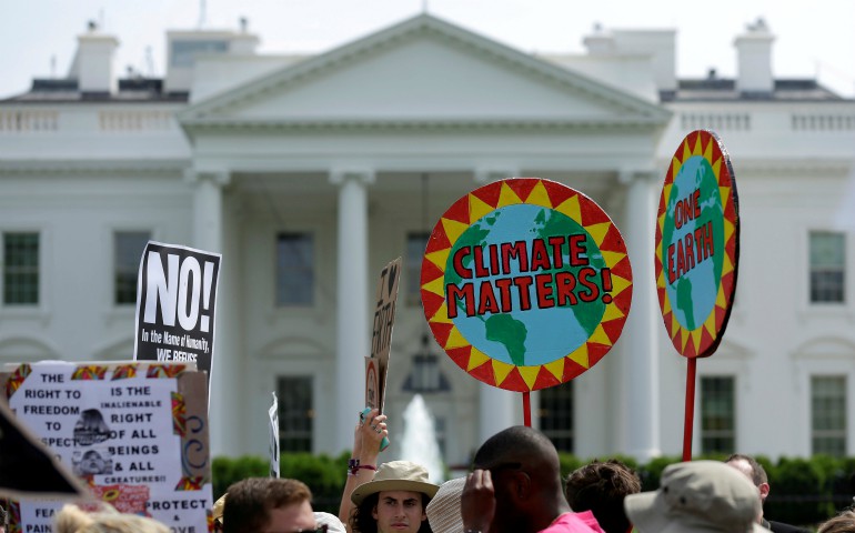 Protesters carry signs during the People's Climate March April 29 outside the White House in Washington. The U.S. bishops June 1 urged President Donald Trump to honor the nation's commitment to the Paris climate pact and protect the planet. (CNS photo/Joshua Roberts) 