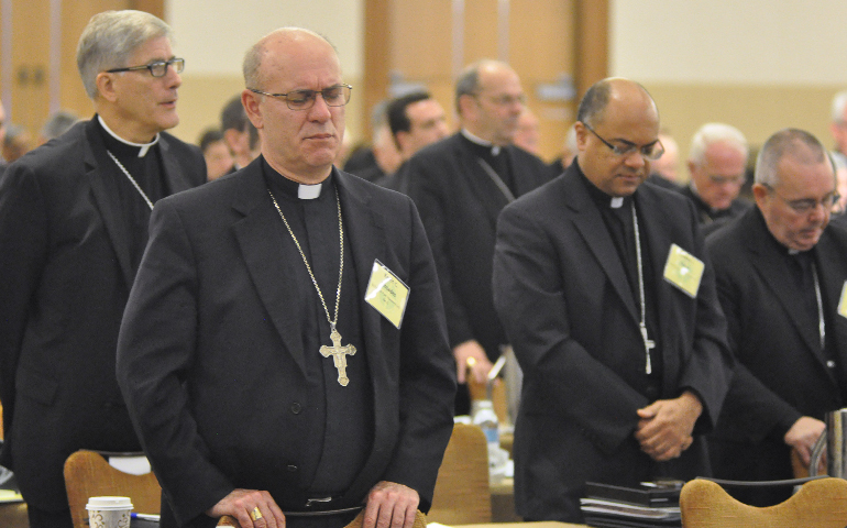 Bishop Kevin C. Rhoades of Fort Wayne-South Bend, Ind., left, and Bishop Shelton J. Fabre of Houma-Thibodaux, La., pray June 14 during the opening session of the U.S. Conference of Catholic Bishops' annual spring assembly in Indianapolis. (CNS/Sean Gallagher, The Criterion)