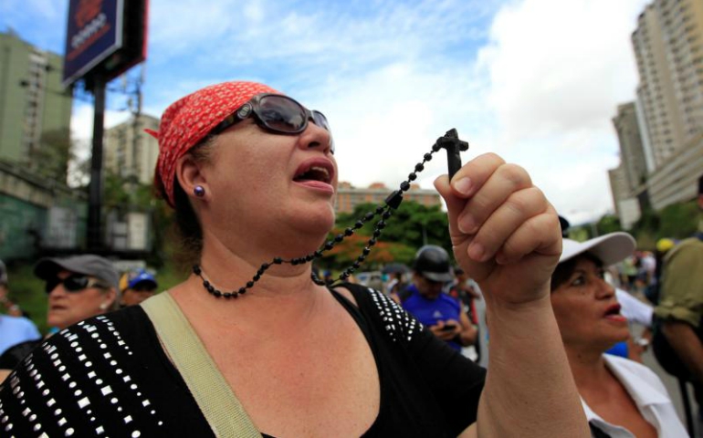 An opposition supporter holds a rosary as she prays with others during a June 14 rally against Venezuelan President Nicolas Maduro's government in Caracas. (CNS /Christian Veron, Reuters)