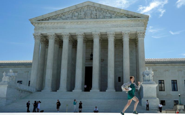 A news assistant runs past the U.S. Supreme Court in Washington after the justices announced they would hear President Donald Trump's travel ban case in October and also said that in the meantime, a limited version of the ban could take effect while the legal battle continues. (CNS/Yuri Gripas, Reuters)