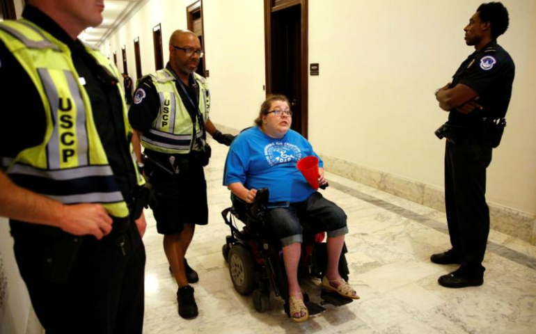 A protester demonstrating against the Senate health care bill is escorted away by police outside Senate Majority Leader Mitch McConnell's constituent office in Washington June 22. (CNS photo/Kevin Lamarque, Reuters)