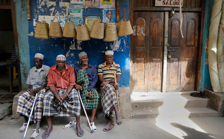 Elderly men sit on a bench in front of souvenir shops in Lamu, Kenya, in this 2014 file photo. Suspected al-Shabab militants have increased attacks in the area, forcing locals to flee into churches. (CNS/Dai Kurokawa, EPA)