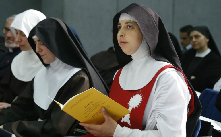 A nun holds a copy of "Cor Orans," a new instruction for contemplative women religious, during a news conference for its release at the Vatican May 15. (CNS / Paul Haring)