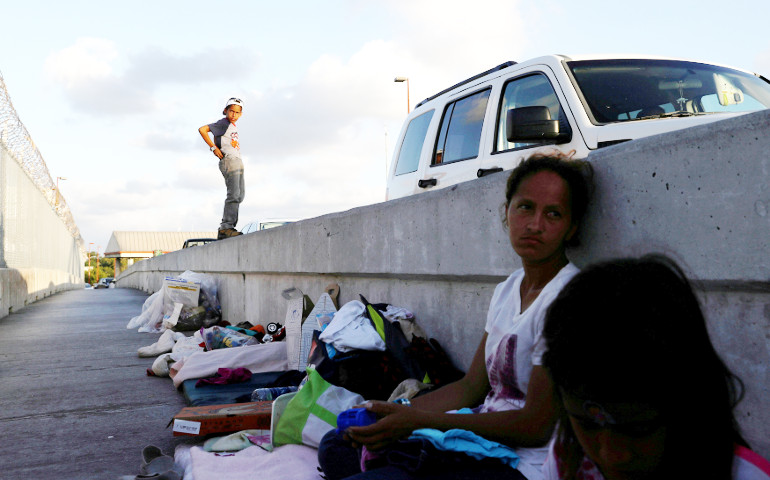 A Honduran family near Brownsville, Texas, rests in the shade June 26 while waiting on the Mexican side of the Brownsville-Matamoros International Bridge after being denied entry by U.S. Customs and Border Protection officers. (CNS / Reuters / Loren Elliott)