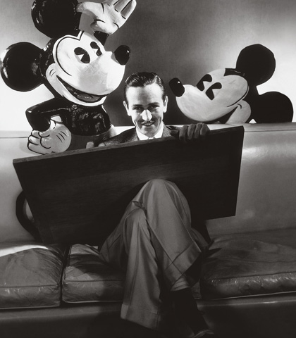 Walt Disney seated with drawing board on his lap and representations of his creations Mickey and Minnie Mouse behind, Oct. 1933. (Courtesy of Condé Nast Archive/Corbis)