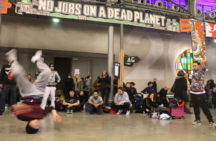 A break dancer shows their moves during a lull between speeches at the Climate Action zone in the Centquarte cultural center in Le Bourget, Paris. (NCR photo/Brian Roewe)