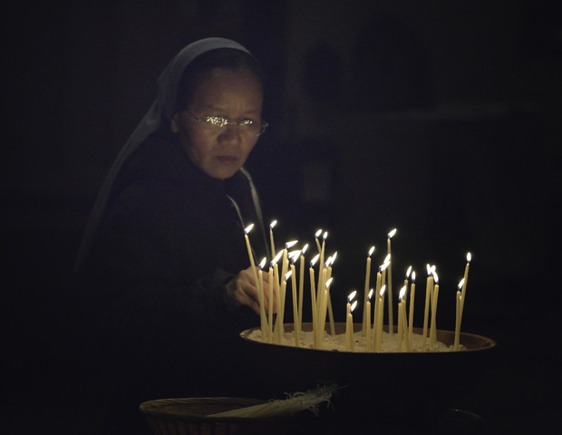 Sr. Hien Nguyen of Vietnam lights candles at a July 22 interfaith service at St. Paul's Anglican Cathedral in Melbourne, Australia. The event was a memorial service for those who have died of HIV- and AIDS-related causes and included the involvement of several delegates to the 20th International AIDS Conference. (CNS/Paul Jeffrey)