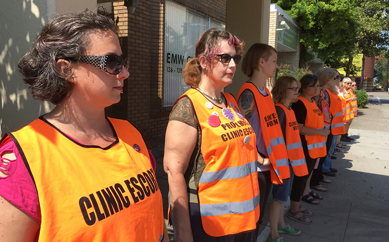 In this Monday, July 17, 2017 photo, Meg Stern, left, and other escort volunteers lined up outside the EMW Women's Surgical Center in Louisville, Ky. (AP Photo/Dylan Lovan)