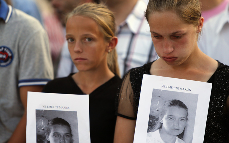Albanian girls hold portraits of a 17-year-old girl who was killed in 2012 with her grandfather in what was called a "blood feud." (CNS/EPA/Armando Babani)