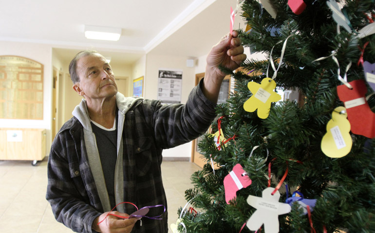 Parishioner Donald Sagristano selects paper ornaments from a Giving Tree at Sts. Philip & James Church in St. James, N.Y., Nov. 28. (CNS/Gregory A. Shemitz) 