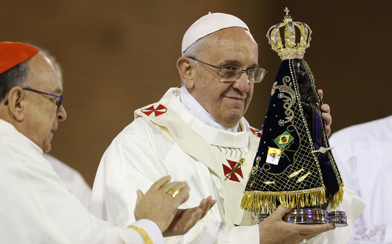 Pope Francis holds up a statue of Our Lady of Aparecida after Cardinal Raymundo Damasceno Assis of Aparecida, left, presented it to him Wednesday at the beginning of Mass at the Basilica of the National Shrine of Our Lady of Aparecida. (CNS/Paul Haring)