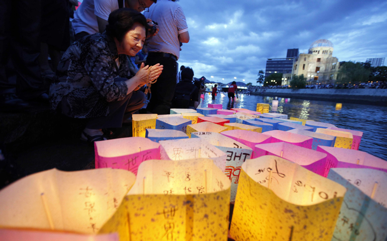 A woman prays after releasing a paper lantern on a river facing the gutted Atomic Bomb Dome in Hiroshima, Japan, on Aug. 6, 2011, the 66th anniversary of the world's first atomic bombing. (CNS/Reuters/Kim Kyung-Hoon)