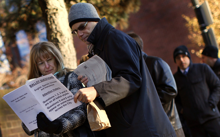 Voters in Boston look over information on ballot questions while waiting at a polling place Tuesday. Massachusetts voters narrowly defeated a "death with dignity" measure, rejecting attempts to legalize assisted suicide. (CNS/Reuters/Mike Segar)