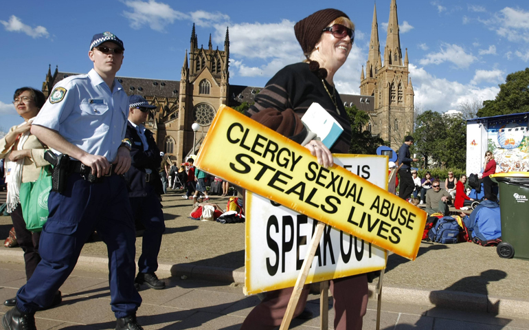 Police officers escort a woman protesting against clergy sexual abuse away from St. Mary's Cathedral in Sydney, Australia, where Pope Benedict XVI was meeting with religious leaders on July 18, 2008. The pope was in Australia for World Youth Day. (CNS/Reuters/Tim Wimborne)