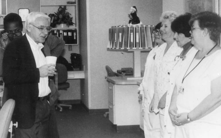 Bishop Kenneth E. Untener chats with staff in a nursing station at St. Mary's Medical Center in Saginaw, Mich., The hospital was the roving bishop's 52nd home since 1980. (CNS file photo, Dec. 1994)