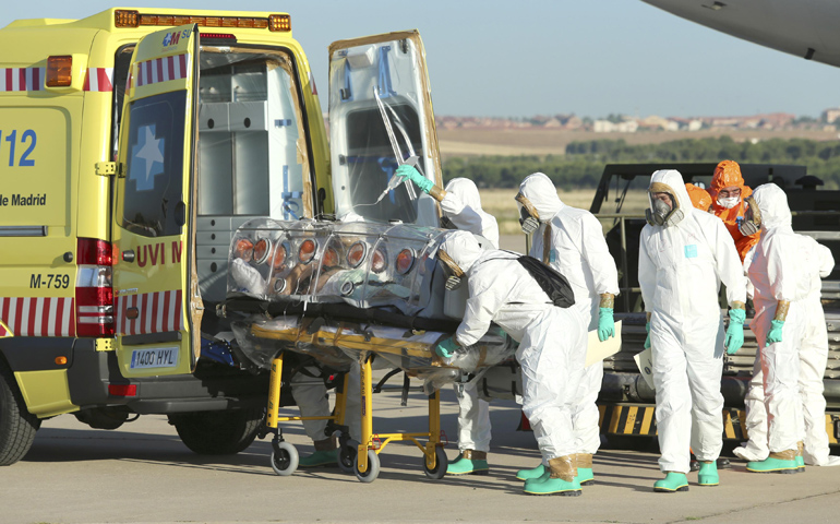 Health workers put Ebola patient Fr. Miguel Pajares of Spain into an ambulance Thursday at a military air base in Madrid after he was repatriated from Liberia for treatment. (CNS/Reuters/Ministry of Defence handout)