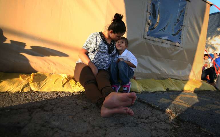 Yesenia Matilde Martinez of Guatemala, kisses her daughter, Leslie Jasmin Martinez, 5, as they wait for their bus ride at the Humanitarian Respite Center on the U.S.-Mexico border in McAllen, Texas. They are among the thousands of families that have stayed at the center after crossing the border from Central America. (GSR photo / Nuri Vallbona)