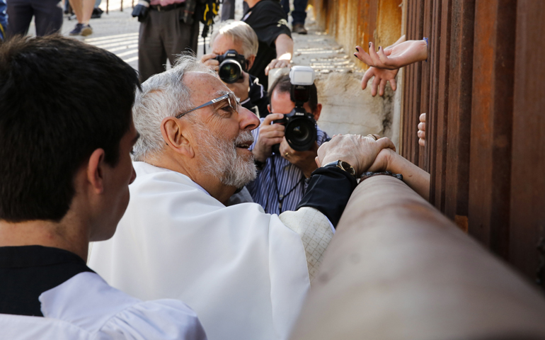 Bishop Gerald Kicanas of Tucson, Ariz., blesses people on the Mexican side of the border as he distributes Communion through the border fence Tuesday in Nogales, Ariz. (CNS/Nancy Wiechec) 