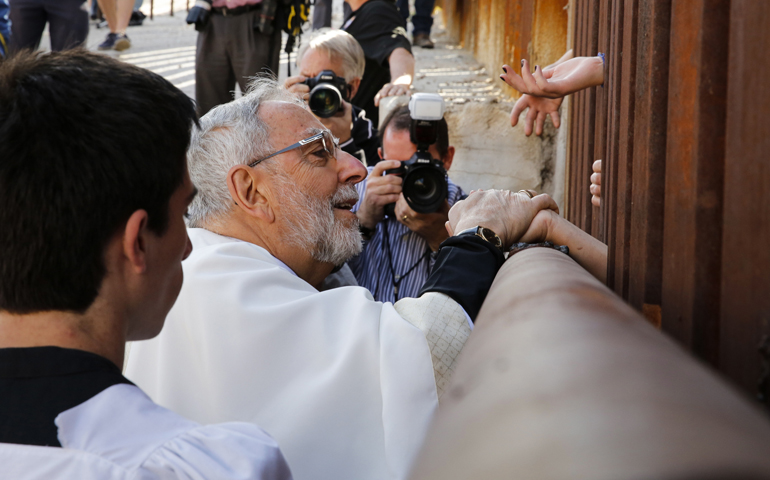 Bishop Gerald Kicanas of Tucson, Ariz., blesses people on the Mexican side of the border as he distributes Communion through the border fence Tuesday in Nogales, Ariz. (CNS/Nancy Wiechec)