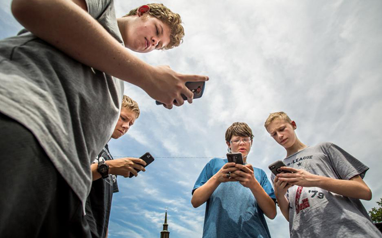 Alec Richardson, Brennan Moore, Adam Salman and Blake Koelz hunt Pokemon around the grounds of Assumption Church in St. Louis on July 14. (CNS/St. Louis Review/Lisa Johnston)