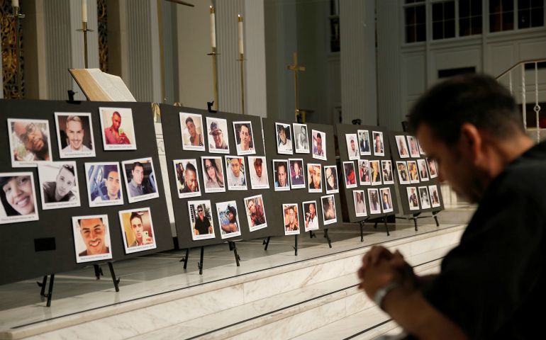 A man prays June 15, 2016, in front of photographs of victims of the mass shooting at the Pulse nightclub in Orlando, Florida, during a vigil at a church in Orlando. (CNS photo/Jim Young, Reuters) 