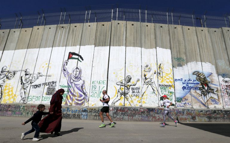Participants run past the controversial Israeli separation barrier during the annual Right to Movement Palestine Marathon in Bethlehem, West Bank, April 1. (CNS photo/Ammar Awad, Reuters)
