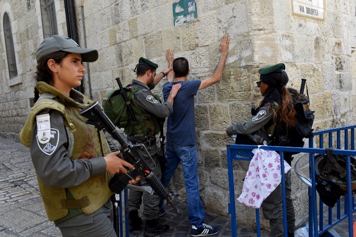Israeli border police make a Palestinian face the wall for a body security check on the Via Dolorosa in Jerusalem's Old City Oct. 18, near a site where several recent stabbings have taken place. (CNS photo/Debbie Hill) 