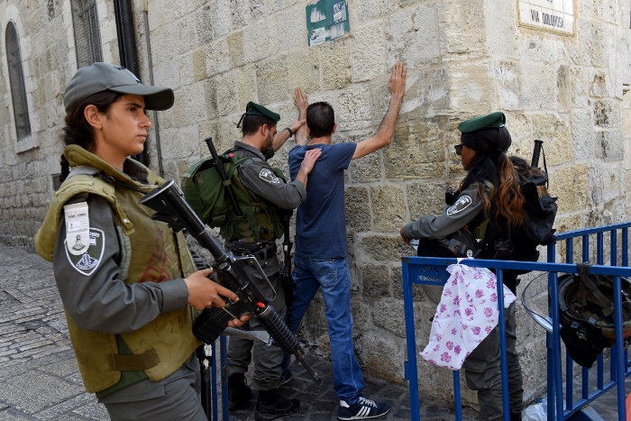 Israeli border police make a Palestinian face the wall for a body security check on the Via Dolorosa in Jerusalem's Old City Oct. 18, near a site where several recent stabbings have taken place. (CNS photo/Debbie Hill)