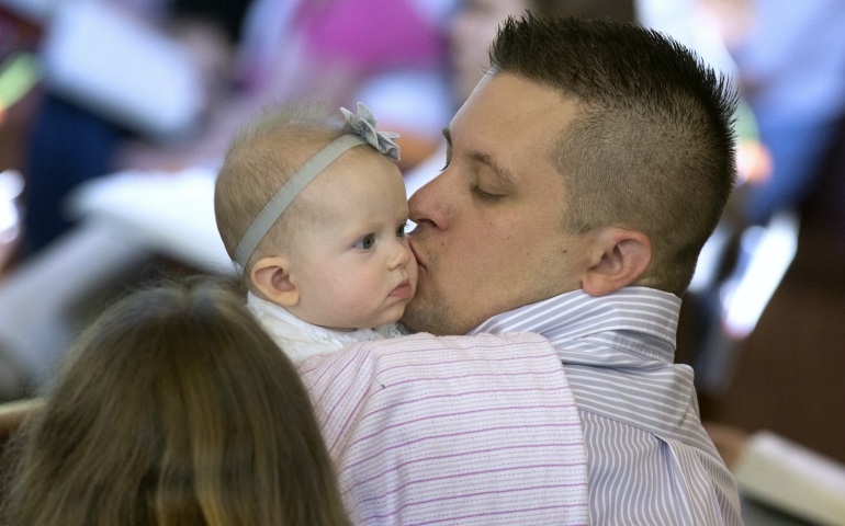 A man kisses his daughter during Mass in 2014 at Jesus the Divine Word Church in Huntingtown, Maryland. (CNS/Bob Roller)