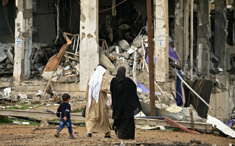 A displaced Iraqi family walks near destroyed buildings March 4 in the Mosul, following a battle between Iraqi forces and Islamic State militants. (CNS photo/Thaier Al-Sudani, Reuters)