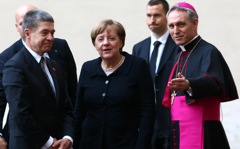 Archbishop Georg Ganswein, prefect of the papal household, right, greets German Chancellor Angela Merkel and her husband, Joachim Sauer, as they arrive March 24 for the European Union summit with Pope Francis at the Vatican. (CNS photo/Alessandro Bianchi, Reuters) 