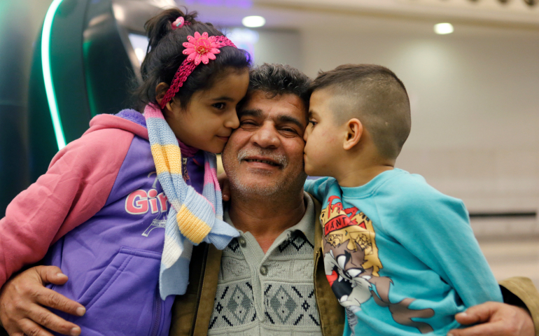 Nizar al-Qassab, an Iraqi Christian refugee from Mosul, gets a kiss from his children as they prepare to depart from Beirut international airport Feb. 8 en route to the United States. (CNS photo/Mohamed Azakir, EPA)