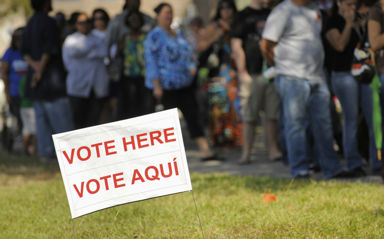 A sign in English and Spanish is seen as people wait to vote in 2012 outside a polling place in Kissimmee, Florida. (CNS photo/Scott A. Miller, Reuters) 