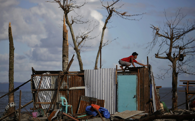 A man repairs his house, which was damaged by Typhoon Haiyan, at a coastal area south of Tacloban Nov. 16. (CNS/Reuters/Damir Sagolj)