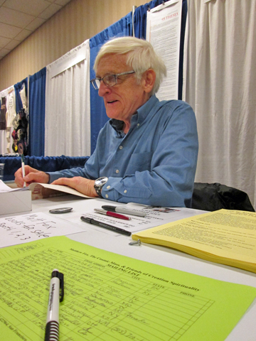 Matthew Fox, a creation theologian and Episcopal priest, signs books at the Call to Action conference in Louisville, Ky. (NCR photo/Zoe Ryan)