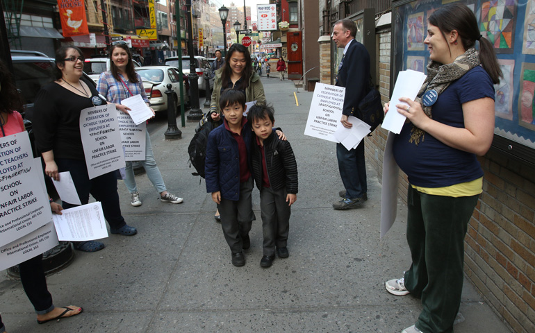 A woman and two students walk past striking teachers May 5 near the entrance of Transfiguration School in the Chinatown section of New York City. (CNS/Gregory A. Shemitz)