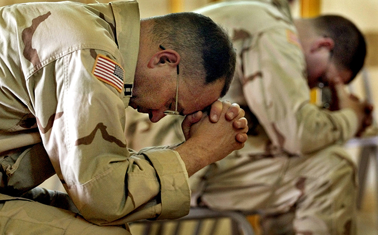 U.S. Army Chaplain Tim Meader, left, and Chaplain William Lovell, both from Fort Carson, Colo., pray during an Easter service at Camp New Jersey in Kuwait on April 20, 2003. (RNS/Reuters/Adrees Latif)