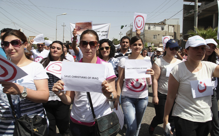 Christian demonstrators in Irbil, Iraq, carry signs as they protest July 24 against militants of the Islamic State. Hundreds of Iraqi Christians marched to the United Nations office in Irbil, calling for help for families who fled in the face of threats by Islamic State militants. (CNS/Reuters)