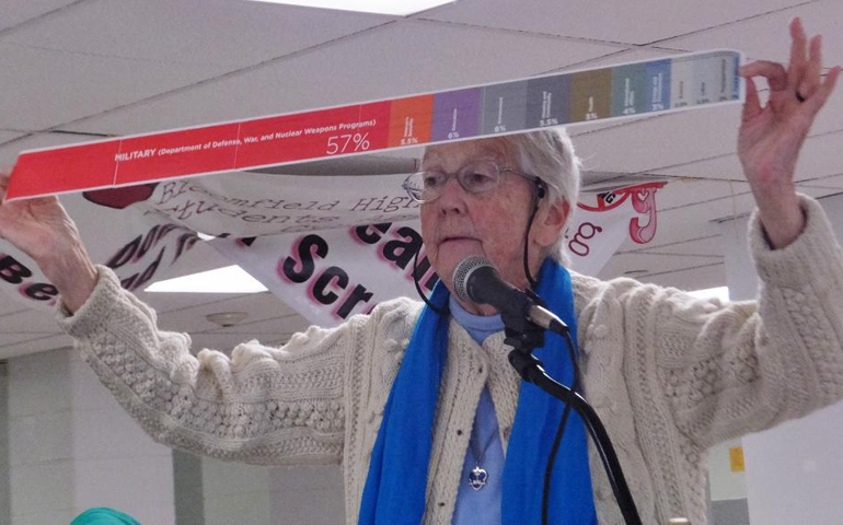 Sr. Megan Rice holds up a measuring scroll produced by the American Friends Service Committee showing that United States spends 57 percent of its revenue on militarism, more than other nuclear-armed nations. (GSR/Patricia Lefevere)