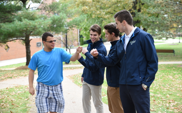 Marco Cicchino, left, an Autism Initiative at Mercyhurst student, greets three members of the Mercyhurst men’s ice hockey team, while walking on campus in 2016. The hockey players, left to right, are Tyler Enns and Jack Riley, both juniors at Mercyhurst, and Spencer Bacon, who graduated last year. (Mercyhurst University)