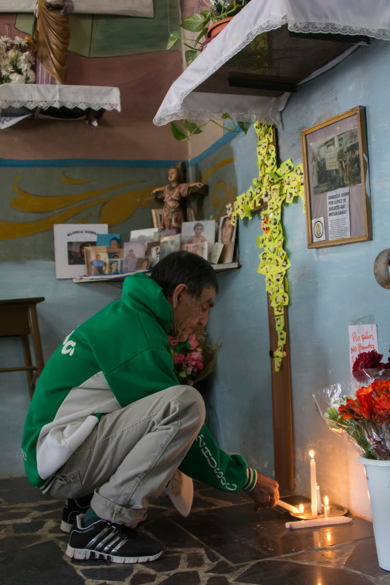 At the Virgin de Caacupé Parish, a local man from Villa 21 lights a candle at a makeshift altar dedicated to youths who have died from violence. (Horacio "Tati" di Renzi)