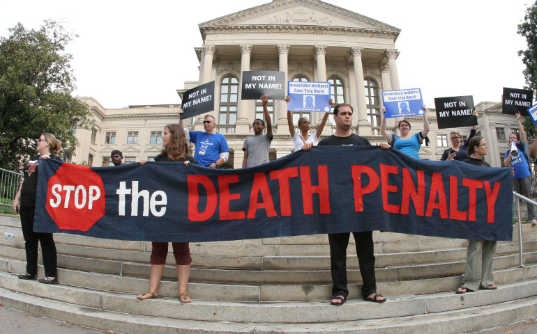 People hold a banner and signs on the steps of the Georgia Capitol in Atlanta during a vigil for death-row inmate Troy Davis before his Sept. 21 execution. (CNS/Georgia Bulletin/Michael Alexander)