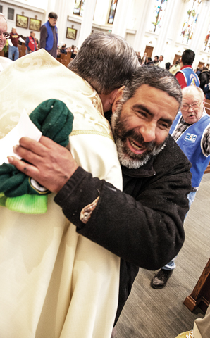 Father Ron Cattany, pastor of Denver's Cathedral Basilica of the Immaculate Conception, shares an embrace with a homeless friend. (Andrew Wright/Courtesy Denver Catholic)