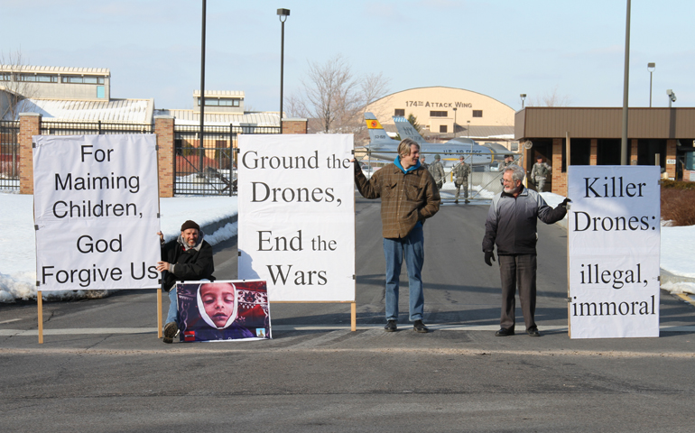 Anti-drone activists, from left, Bill Frankel-Streit, Matt Ryan and Jim Clune hold signs in front of the 174th Attack Wing of the Air National Guard on Ash Wednesday, Feb. 13, in DeWitt, N.Y. (Daniel Burns)