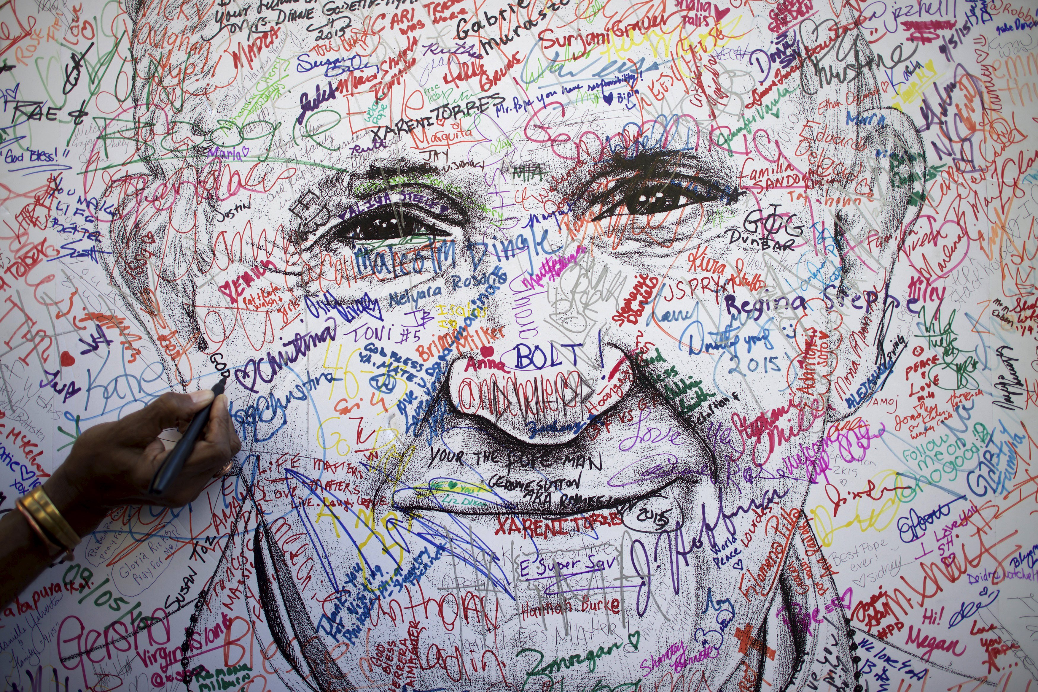A delegate to the 2015 World Meeting of Families signs a poster drawing of Pope Francis by artist Mark Gaines Sept. 23 in Philadelphia.(CNS photo/Mark Makela, Reuters)